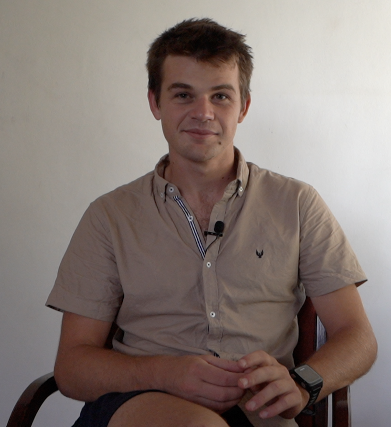 A young man sitting in a chair in an empty room.